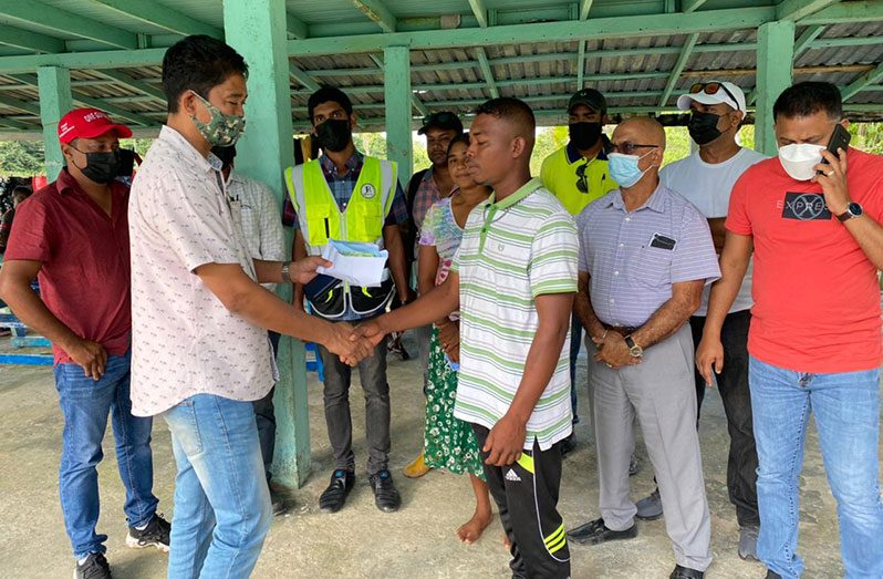 Fire victim Joshua Samuels Gill (left) is engaged by Minister within the Ministry of Public Works Deodat Indar (extreme right) and PSC Chairman Paul Cheong (centre)