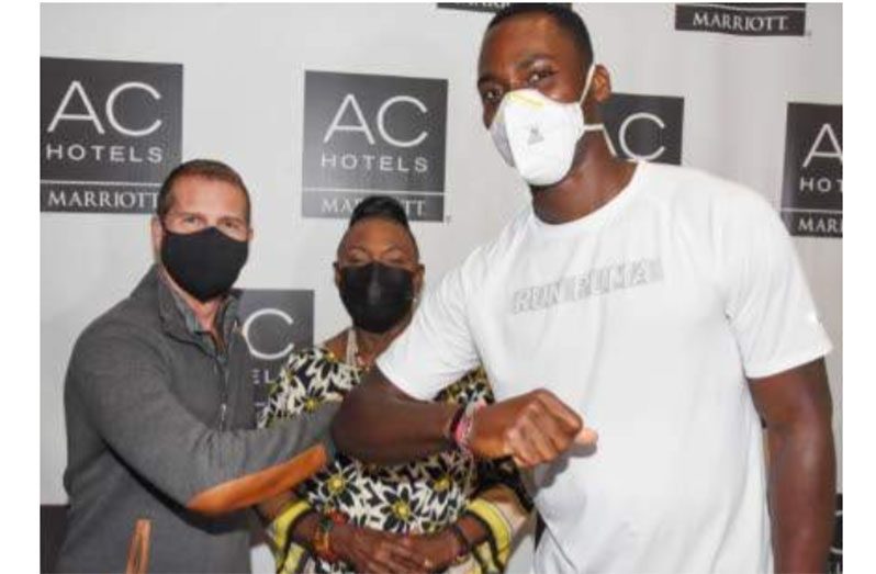 Olympics 110-metre hurdles champion Hansle Parchment (right) is welcomed to the AC Hotel in Kingston, Jamaica on Sunday by Sandals Resorts International Executive Chairman Adam Stewart. At centre is Minister of Sports Olivia “Babsy” Grange. (Jamaica Observer picture)
