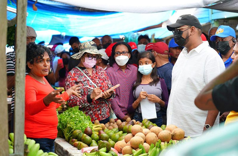 President Dr. Irfaan Ali and other officials listen to the concerns of a vendor at the Parika Market (Latchman Singh photo)