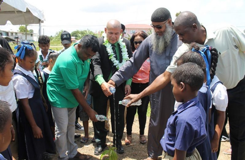 Minister George Norton along with community leaders with schoolchildren who witnessed the watering of the first plant.