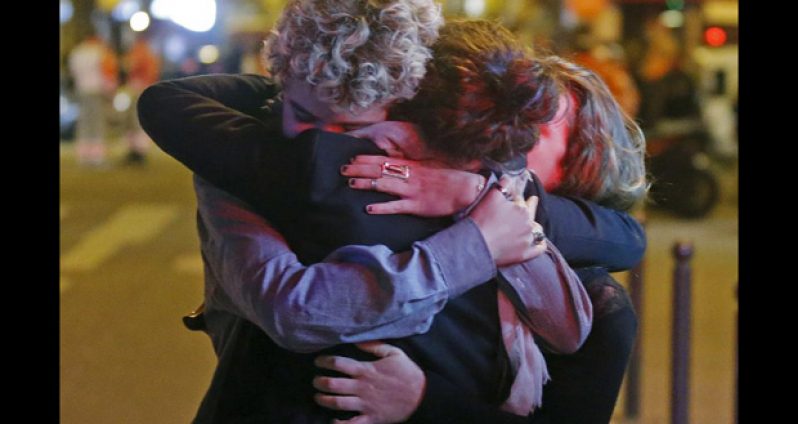 People hug on the street near the Bataclan concert hall following fatal attacks in Paris, France, November 14, 2015. (REUTERS/Christian Hartmann)