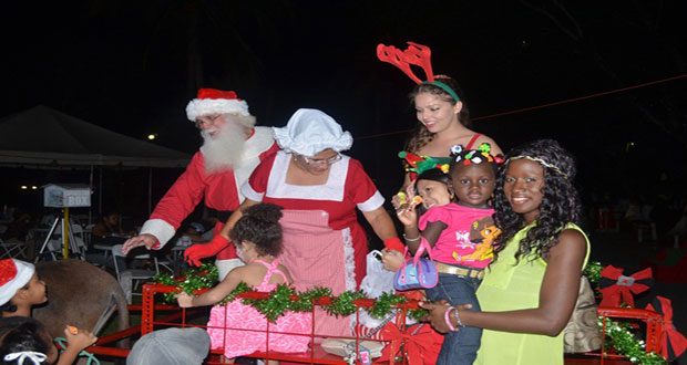 Families receiving treats from Santa and his helpers Friday at the Ministry of Natural Resources and the Environment’s Protected Areas Commission’s Christmas Family Festival and Christmas Tree Light-up at the National Park