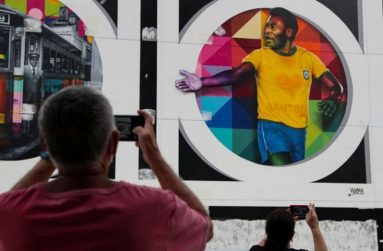 People take pictures of a mural depicting Brazilian soccer legend Pele in Santos.