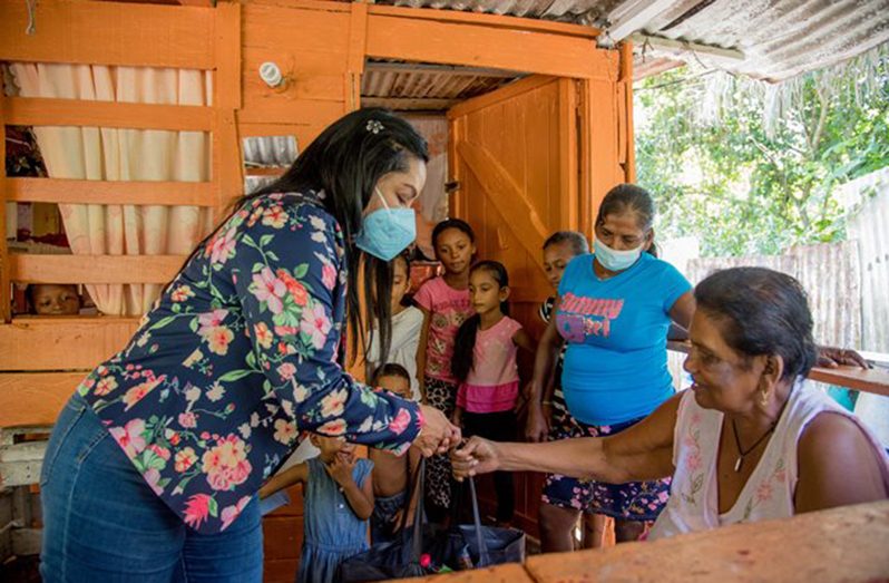 Minister of Human Services and Social Security, Dr. Vindhya Persaud, hands over a hamper to a resident
