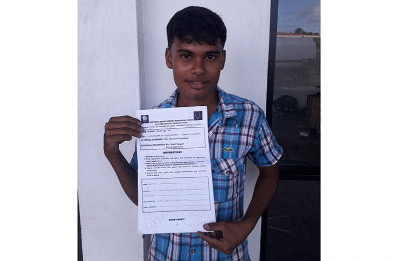 Aunkaar Persaud displays the examination paper after gaining a 90% pass grade.