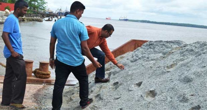 Minister of Natural Resources and the Environment, Mr. Robert Persaud, examines the stone whilst Mr Vishnu Ramdial of Durban Quarries looks on