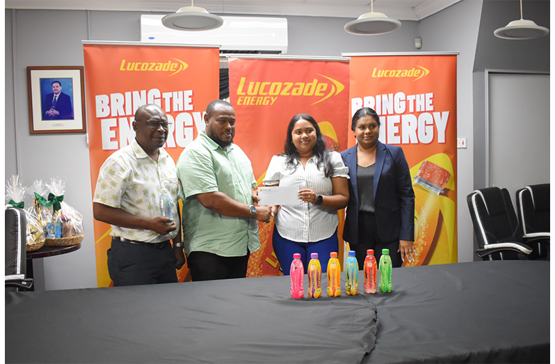Darshanie Yusuf-Abel, Divisional Head, Beverage (far right) and troy Peters (far left) loos on as Petra Director Troy Mendonca collects Cheque from Christina Beepat, Brand Manager Lucozade