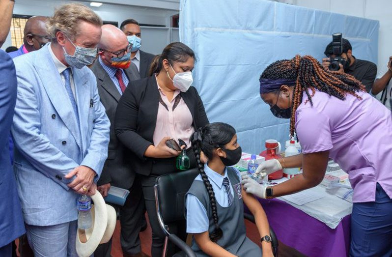 Minister of Education, Priya Manickchand, looks on as 12-year-old Danah Shiwgobin receives her first dose of the Pfizer-BioNTech COVID-19 vaccine at St. Stanislaus College, in August (Delano Williams photo)