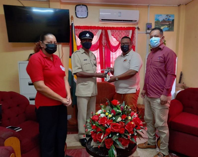 Divisional Commander, Superintendent Boodnarine Persaud, receives the cell phone from Regional Chairman, Region One, Brentnol Ashley. Also pictured are Mayor Chris Phang and Deputy Mayor, Mrs. Carolyn Robinson