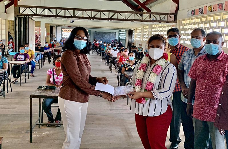 Minister of Education, Priya Manickchand, hands over a voucher to the headmistress (ag) of the Tagore Memorial Secondary School, Sabereena Supaul