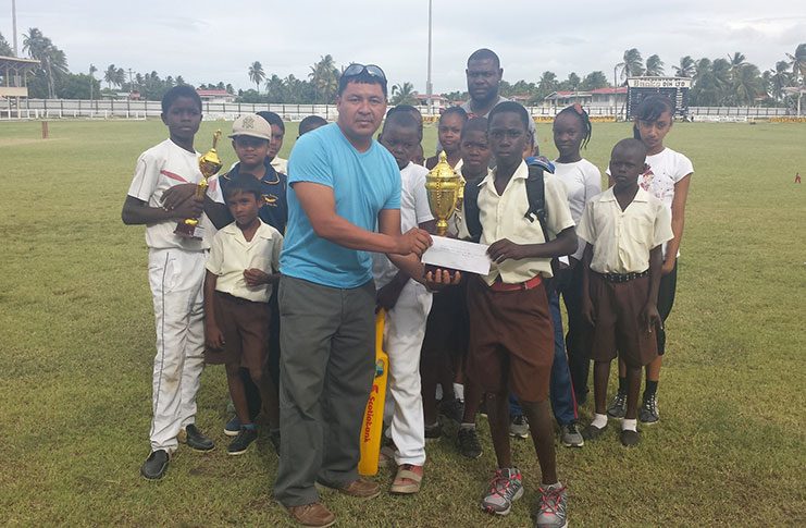 Mr. James Campbell (right), a representative of Sueria Manufacturing , presenting the winning trophy and cash incentive to the captain of the Fyrish Primary School.