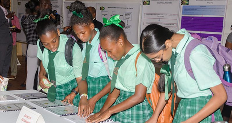 Some of the students present at Wednesday’s launch examine brochures which provide useful information on TVET and its relevance to the Caribbean