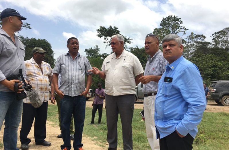 Agriculture Minister Noel Holder (third right), Junior Finance Minister Jaipaul Sharma (right), the prime minister’s representative for Region Six Gobin Harbajan (second right), Mohindra Persaud of Nand Persaud and Company Limited (fourth right) and others make a stop to overlook a canal on the access road  that leads to rice lands in the 52/74 scheme