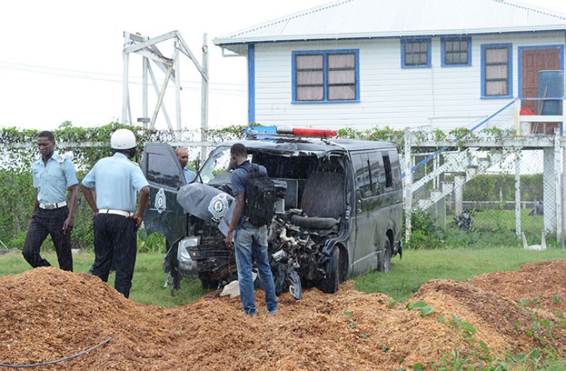 Policemen in the rain inspect the damaged 15-seater minibus as they attached a winch cable of a tow truck to remove the vehicle from the Leonora Police Station Compound.