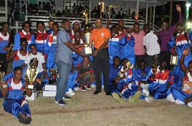 Police Commissioner Seelall Persaud (right) hands over the champion trophy to Headquarters Manager, Senior Superintendant of Police Paul Williams, as Headquarters athletes cheer on (Delano Williams photo)
