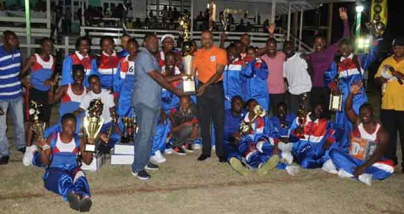 Police Commissioner Seelall Persaud (right) hands over the champion trophy to Headquarters Manager, Senior Superintendant of Police Paul Williams, as Headquarters athletes cheer on (Delano Williams photo)