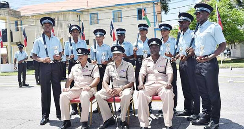 Assistant Commissioner of Police David Ramnarine, Commissioner Seelall Persaud and Roston Andires-Junor, pose with the eight top awardees of the latest police recruit training course.