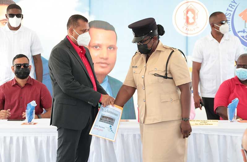 Woman Police Inspector, Haldah Giles pulls her lot number from a bag held by Minister of Housing and Water, Collin Croal