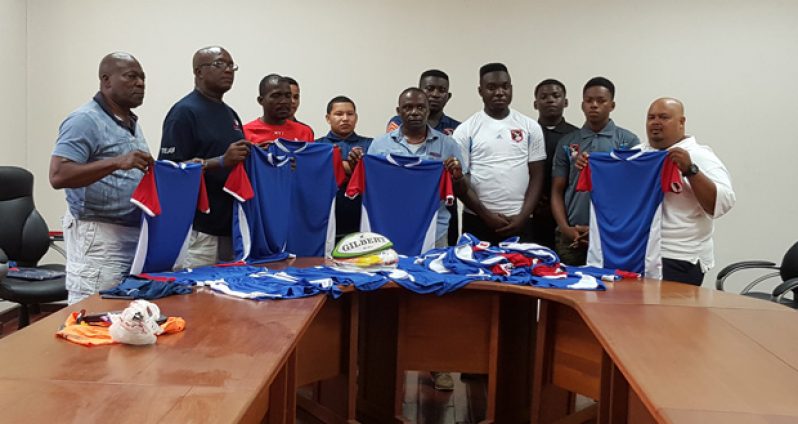 The players of the Police Rugby Team look on as Franklyn Victor (third from left) hands over the uniforms to Police Superintendent Paul Williams