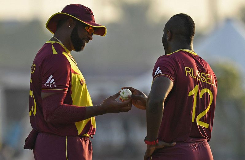 Kieron Pollard hands the ball to Andre Russell , November 5, 2021 (AFP/Getty Images)