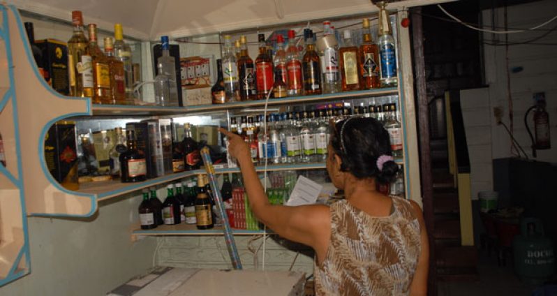 Dhanmatti Ramjass as she points to the spot in the bar where several bottles of liquor were taken by the robbers, who stormed her Pools Bar Wednesday night. (Sonell Nelson photo)