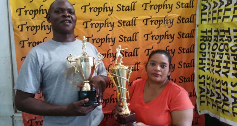 GBA’s Technical Director Terrence Poole (left) and Trophy Stall’s representative Petal Hassna show off some of the silverware that will up for the taking tonight.