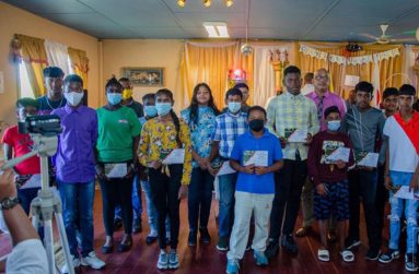 Some players pose with the children of Poonai Bhigroog after receiving their Kadar Bhigroog educational grants