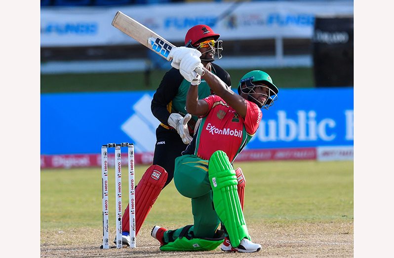 Nicolas Pooran of Guyana Amazon Warriors hits a six as Denesh Ramdin, the wicketkeeper of St Kitts & Nevis Patriots watch during the Hero Caribbean Premier League match at the Queen's Park Oval in Port-of-Spain in September 2020. He scored 100 runs. (Photo by Randy Brooks - CPL T20/CPL T20 via Getty Images)