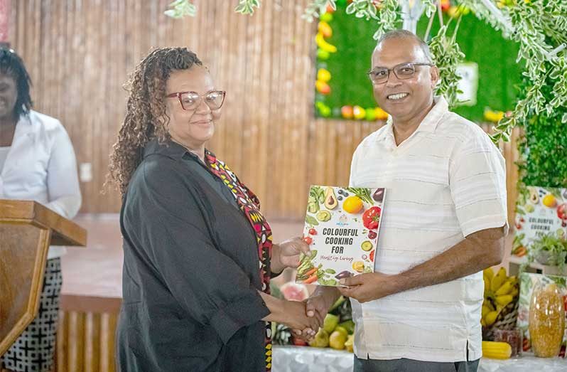 Minister of Health, Dr. Frank Anthony, presents the recipe book to Culinary Specialist, Penelope Harris, who assisted in testing all the recipes and ingredients before the book was prepared (Delano Williams photo)