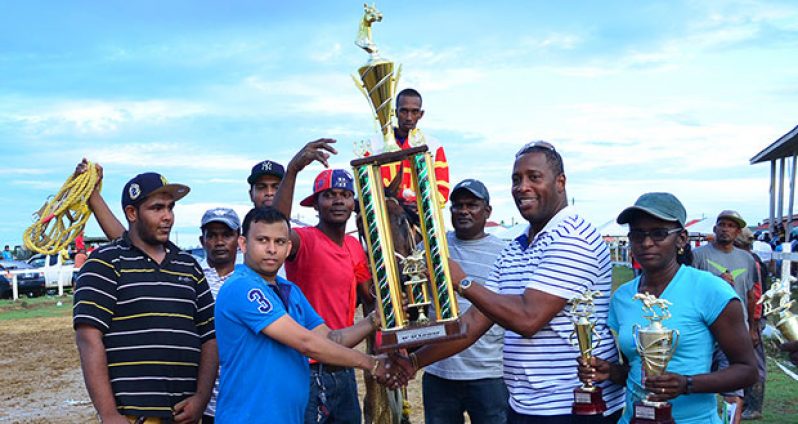Banks DIH representative, Mortimer Stewart, hands over the winning trophy for Release De Beast’s victory in the feature D and Lower race.