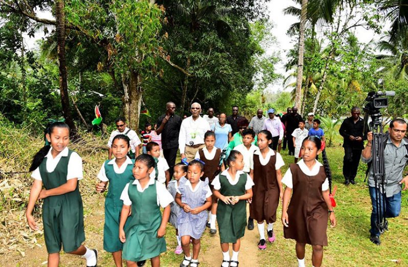 President David Granger and Minister of Social Protection, Ms. Amna Ally, being escorted into Kabakaburi Village by these children 