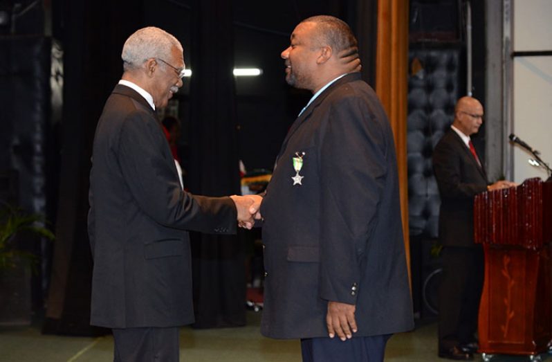 Hilbert Foster receives his Medal of Service Award from President David Granger.