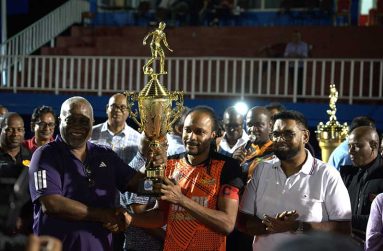 President Dr. Irfaan Ali (right) and Prime Minister Mark Phillips hand over the trophy to Slingerz FC’s Quincy Adams (PHOTO: Slingerz FC)