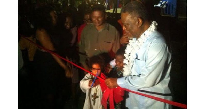 Prime Minister Samuel Hinds, aided by a young girl, cuts the symbolic ribbon to officially
commission the project