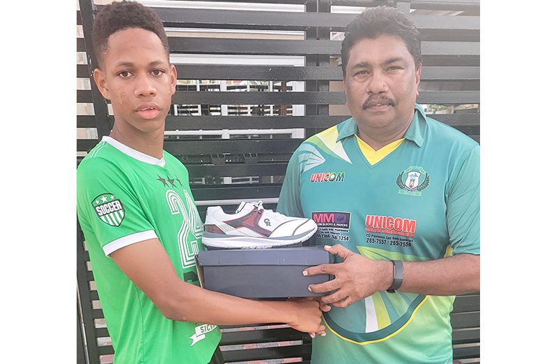 Shane Prince (left) receives a pair of cricket shoes from Anil Beharry.