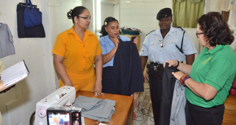 Two inmates at the New Amsterdam Prison show First Lady Mrs Sandra Granger some of the items that they have made, when she toured the prison’s sewing room