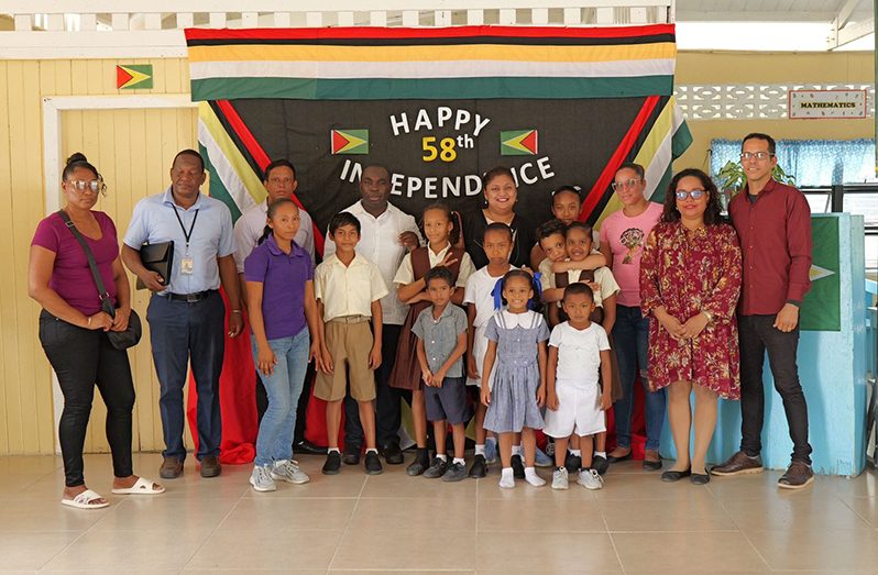 The Minister of Education, Priya Manickchand, and the Minister within the Office of the Prime Minister, Kwame McCoy flanked by local officials and pupils from one of the schools in the riverain communities
