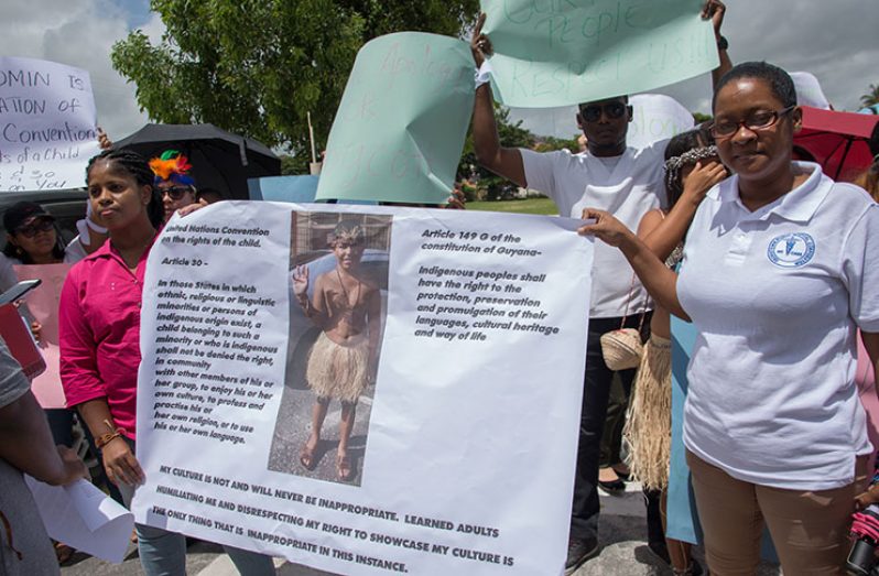 Karen Small (left) and a relative holding up a placard with the photo of her son at the centre bordered by Article 30 of the United Nations Convention on the Rights of the Child on Tuesday in front of Mae’s School.