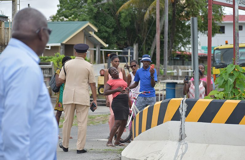A senior police officer engages a small group of persons during the June 28 protest along the East Coast of Demerara (ECD) corridor as Home Affairs Minister, Robeson Benn, looks on (Elvin Croker photo)