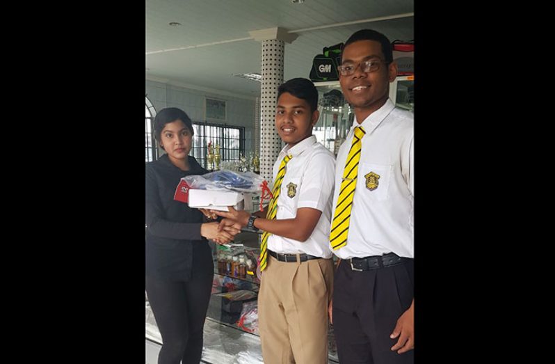 Vice-captain of the QC cricket team, Amos Sarwan, receives the donation from a Star Sports representative. Also in photo is team member Ronaldo McGarrell.