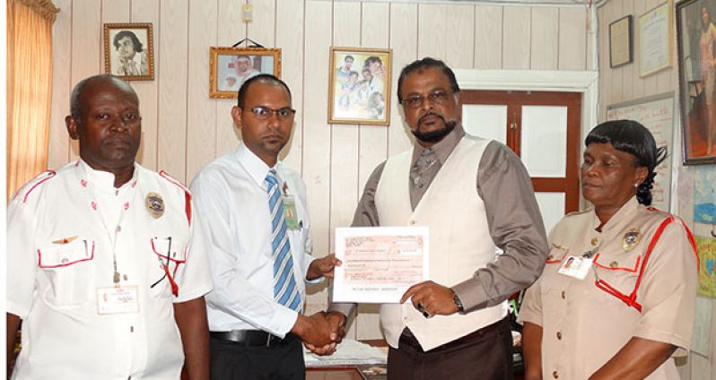 At centre, Mr. Roshan Khan presents cheque to Accountant Derek Sukhram  of Dr. Balwant Singh’s Hospital.  Looking on at left is Security Adviser Colin Boodie and at right – General  Manager, Ingrid Abrams
