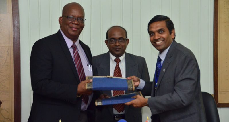 Minister of Finance Winston Jordan (left) hands over a signed copy of the US$50M concessional loan agreement with the Government of India to the resident representative of Export-Import Bank of India T.D. Sivakumar (Right) in the presence of Indian High Commissioner to Guyana Venkatachalam Mahalingam (Center).