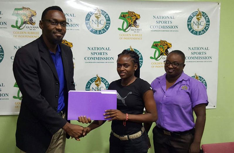 Director of Sport Christopher Jones (left) hands over a signed MOU with sprinter Onessha Rogers in the presence of her mother yesterday.