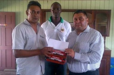 President of the DCB, Rajendra Singh (right), hands over a cheque and some cricket balls to Anil Persaud, to assist the committee with their competition and other administrative commitments, in the presence of GCB Senior Chairman of Selectors, Rayon Griffith.