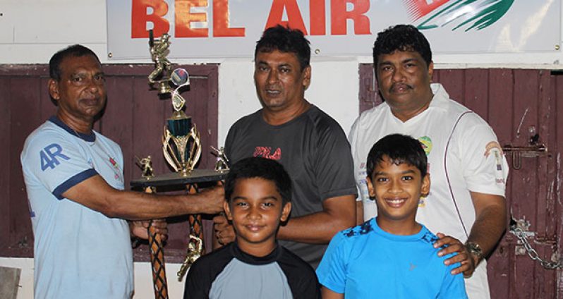 Left is Ramesh Sunich of Trophy Stall handing over the winning trophy to Anil Persaud of East Coast Cricket Committee in the presence of two Under-15 players and GFSCA representative Anil Beharry.