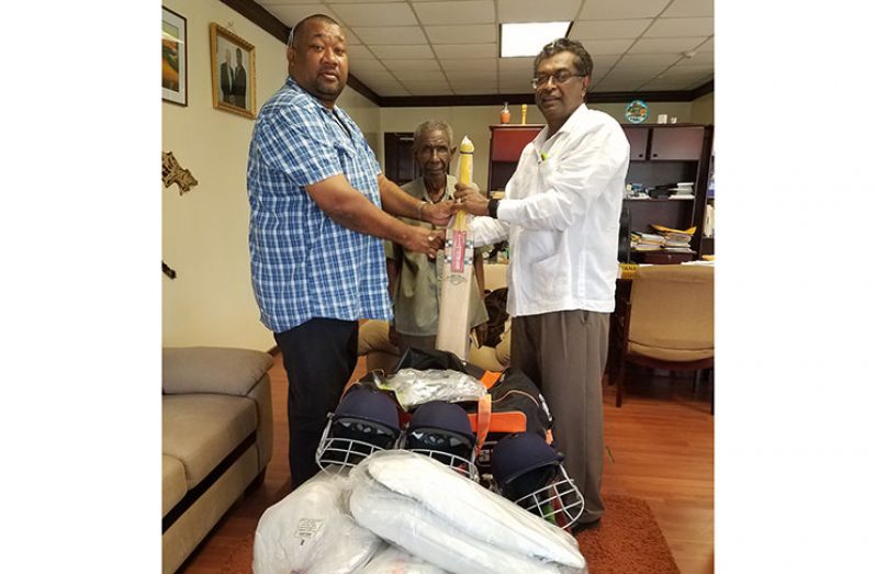 Vice President Khemraj Ramjattan hands over cricket gear to BCB president Hilbert Foster  
 as Malcolm Peters looks on.