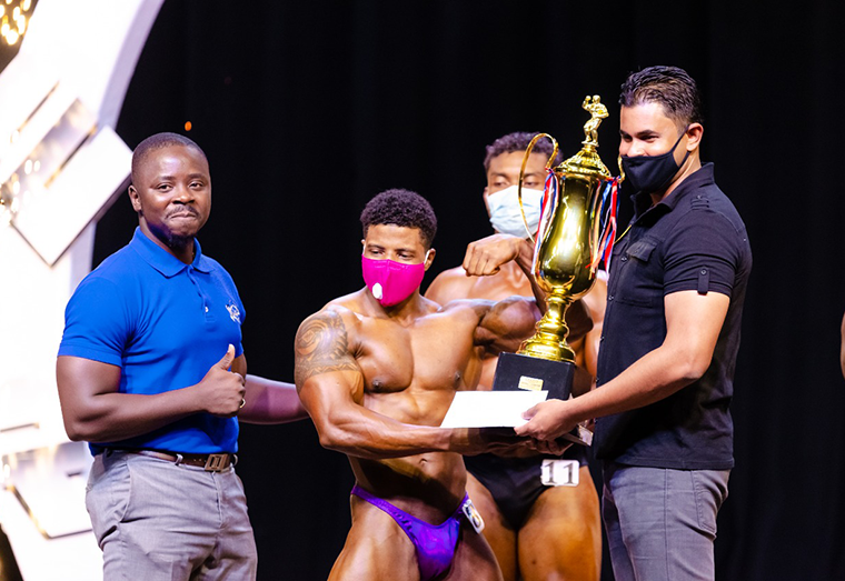 Darious Ramsammy won the 165 and Under division and the Overall Bodybuilding title, which earned him $300,000. Here, he collects his prizes from Minister of Culture, Youth and Sport, Charles Ramson. (Delano Williams photo)