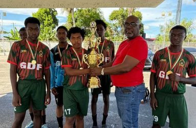 GFF Vice-President Rawlston Adams presents the championship trophy to members of the GDF team (Photo: GFF)