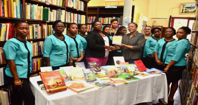 Chief Librarian, Emiley King (fourth left) receives a book donation from President of the Georgetown Rotary Club, Renata Chuck-a-Sang to be passed on to the Kuru Kururu Library