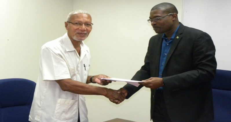 Minister of Public Infrastructure, David Patterson, hands over the agreement to Chairman of the Berbice Bridge Company Incorporated (BBCI), Egbert Carter.